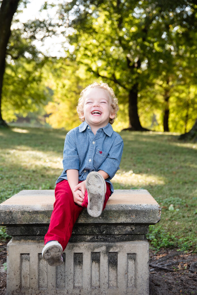 2 year old boy sitting on pedestal laughing in Orlando, Florida