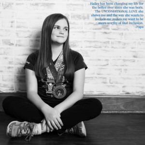 Preteen girl wearing race medals and leaning against a brick wall