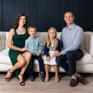 Brunette woman, blonde boy, blonde girl, and dark blonde man sitting for a family photo in a studio in Orlando Florida Brunette woman, blonde boy, blonde girl, and dark blonde man sitting for a family photo in a studio in Orlando Florida