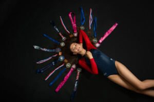 Photo of preteen 11 year old gymnast laying on black background with competition medals in studio in Ocoee Florida. Gymnast photography