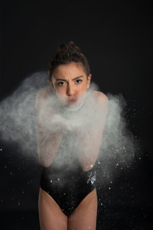 Photo of preteen 11 year old gymnast with powder posing on black background in studio in Ocoee Florida. Gymnast photography